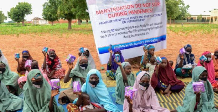 The women and girls displaying the menstrual pad they were given. Photo Credit – Justina Asishana